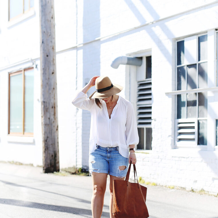 Denim cut-offs, white blouse, floppy hat, leather tote.