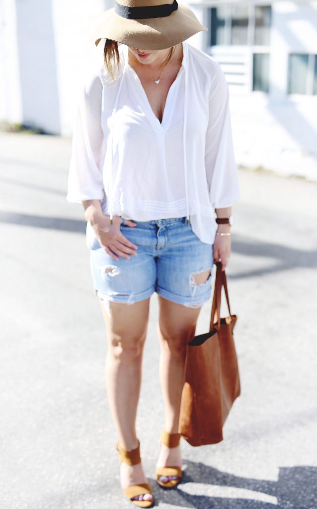 Denim boyfriend cut-off shorts, suede heels, oversized leather tote, sheer white blouse, floppy tan hat.