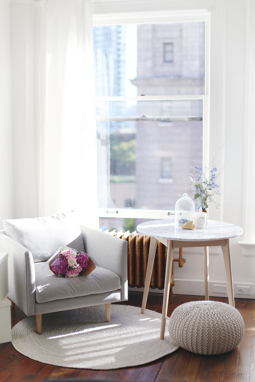 Airy studio space decor tips with marble coffee table, grey minimalist armchair, jute rug and Moroccan pouf by Article furniture