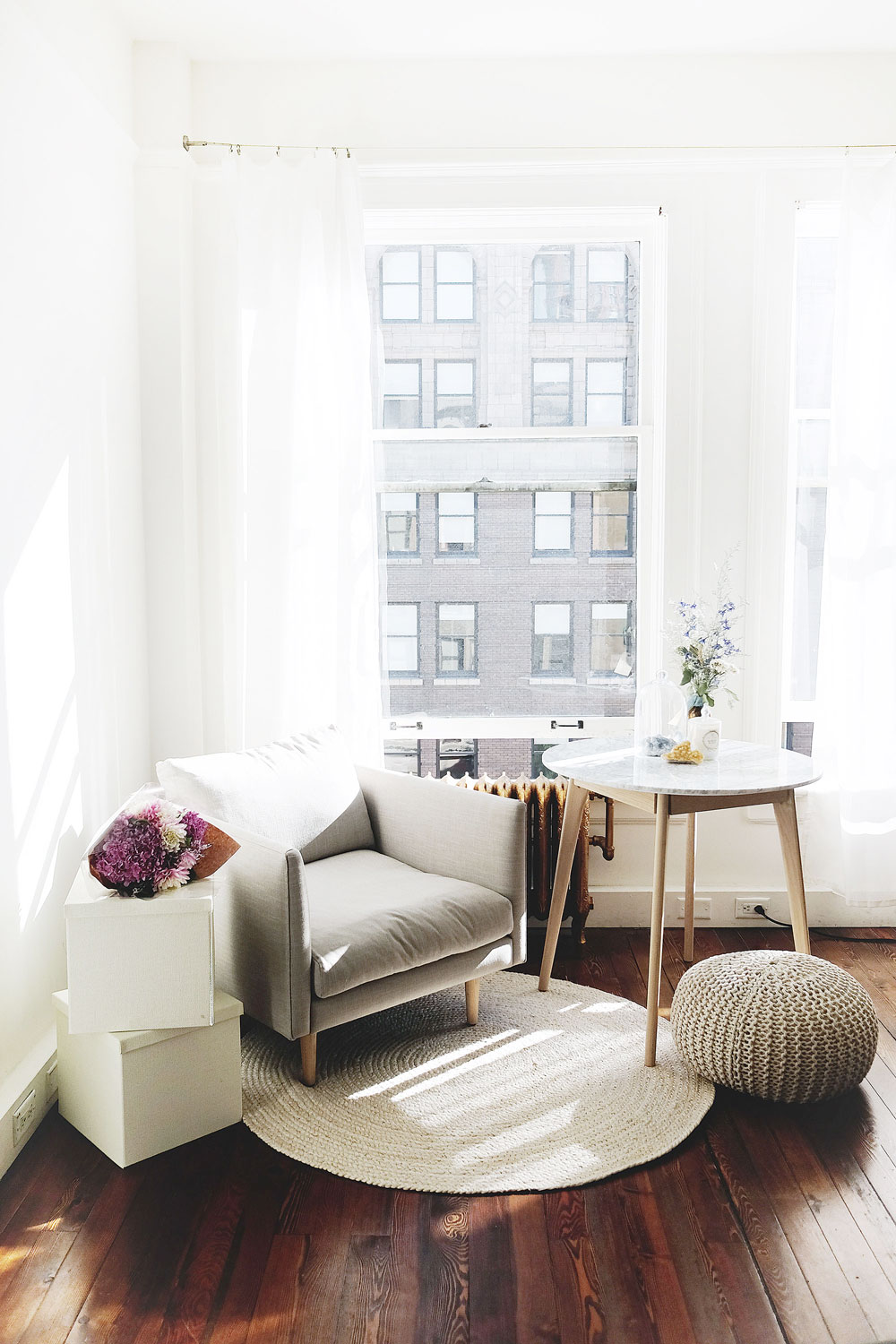 Airy studio space decor tips with marble coffee table, grey minimalist armchair, jute rug and Moroccan pouf by Article furniture