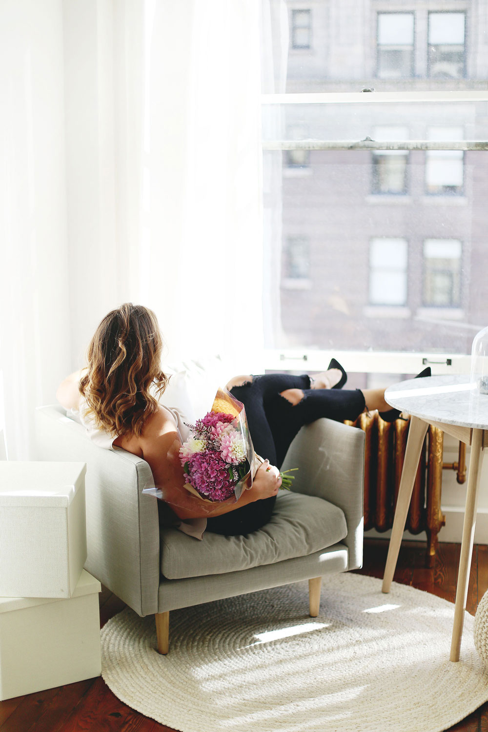 Airy studio space decor tips with marble coffee table, grey minimalist armchair, jute rug and Moroccan pouf by Article furniture