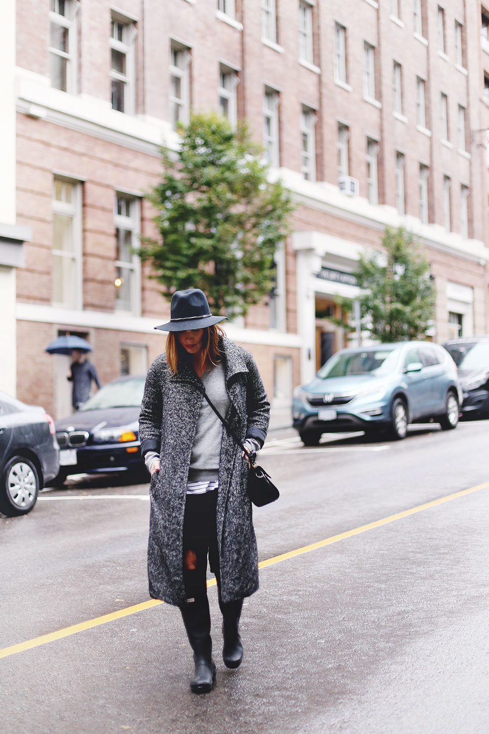 Rainy day outfit ideas for fall, featuring Aritzia Babaton wool trench coat, White and Warren cashmere sweater, striped tank top, Express black wool fedora, Mezzi Mini Cosma bag, Hunter rain boots