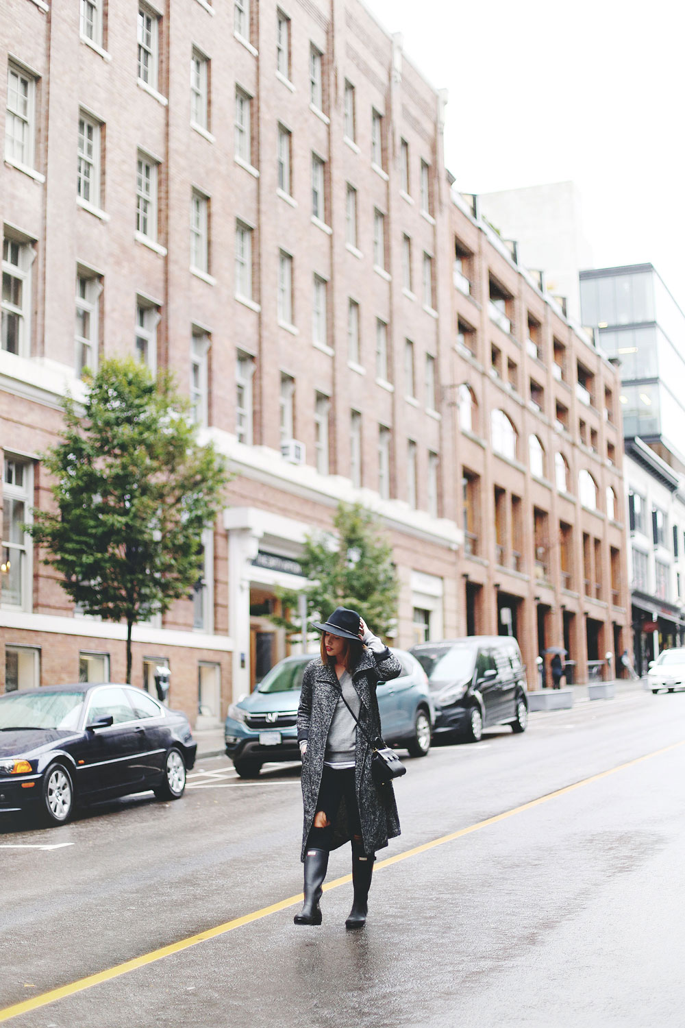 Rainy day outfit ideas for fall, featuring Aritzia Babaton wool trench coat, White and Warren cashmere sweater, striped tank top, Express black wool fedora, Mezzi Mini Cosma bag, Hunter rain boots