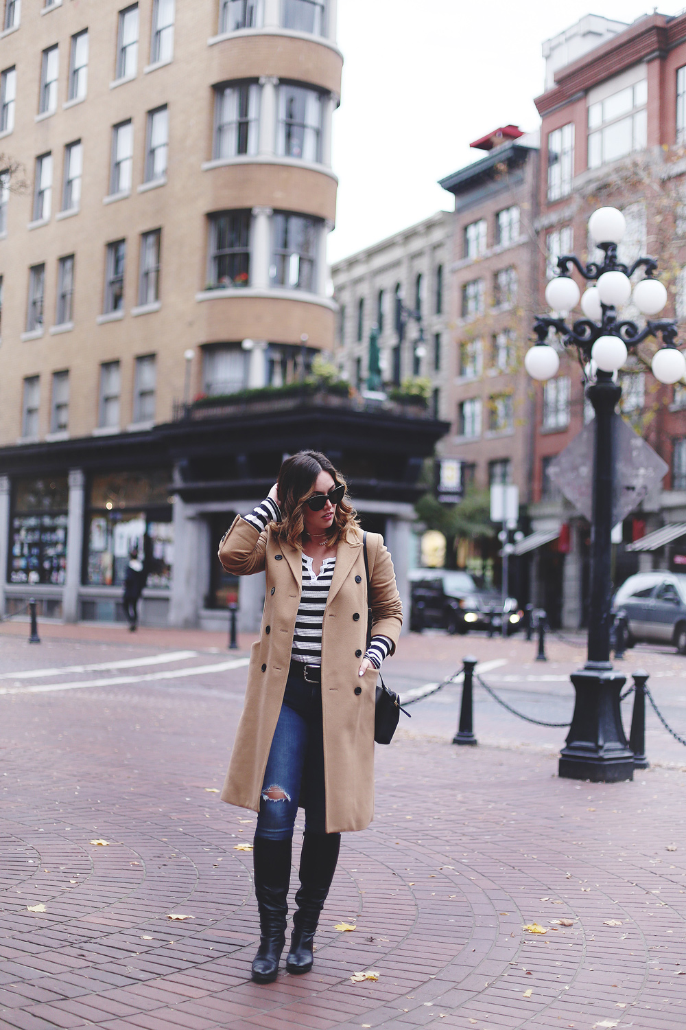 To Vogue or Bust shares camel coat outfit ideas in a camel Aritzia wilfred coat, Mavi skinny jeans, striped Gentle Fawn top, La Canadienne boots and Celine sunglasses in Gastown, Vancouver