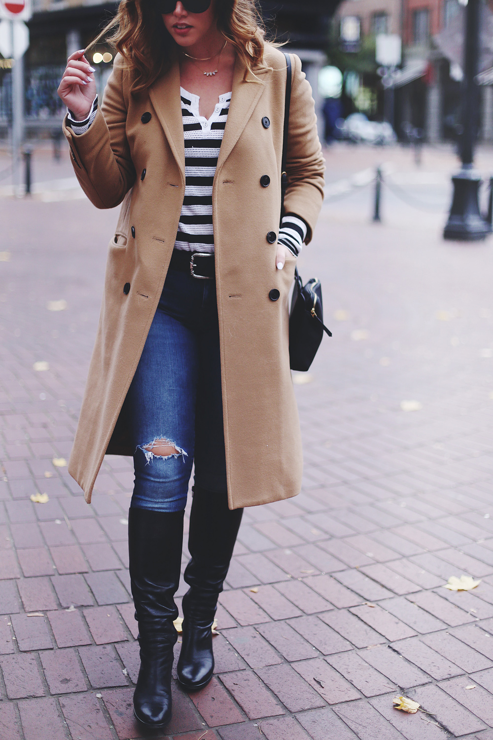 To Vogue or Bust shares camel coat outfit ideas in a camel Aritzia wilfred coat, Mavi skinny jeans, striped Gentle Fawn top, La Canadienne boots and Celine sunglasses in Gastown, Vancouver