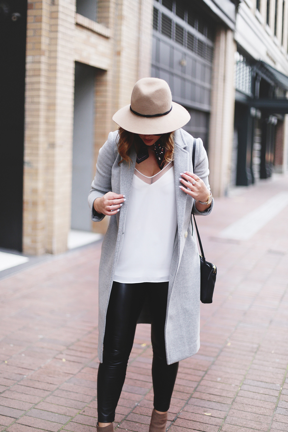 Legging leather outfit tips in Aritzia leather leggings, Aritzia silk camisole, Aritzia wool grey coat, Express tan fedora, Aritzia silk scarf, Aritzia black leather bag, CLUSE mesh silver watch and Urban Outfitters suede ankle boots styled by To Vogue or Bust