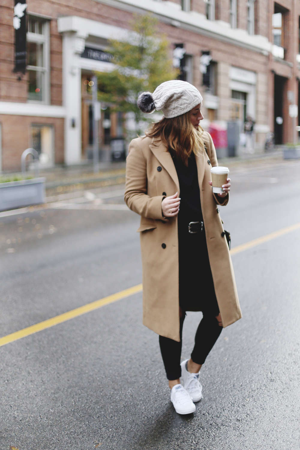 To Vogue or Bust shares ways to style your converse sneakers in white Converse All Stars, Aritzia camel coat, James Jeans black skinny jeans, Aritzia black leather bag and a Tilley Hats beanie