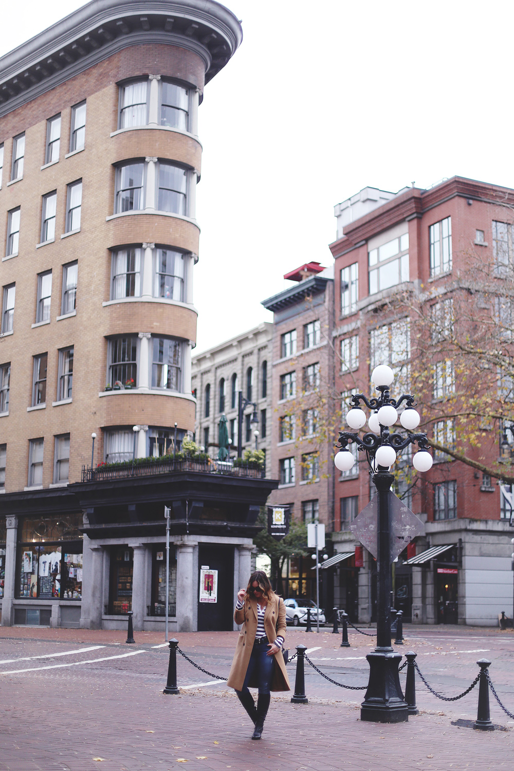 To Vogue or Bust shares camel coat outfit ideas in a camel Aritzia wilfred coat, Mavi skinny jeans, striped Gentle Fawn top, La Canadienne boots and Celine sunglasses in Gastown, Vancouver