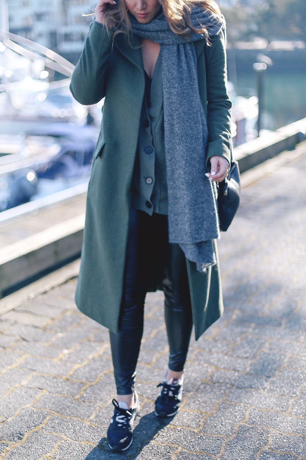Tips to style sneakers in New Balance sneakers, a statement green coat, leather leggings and cashmere cardigan