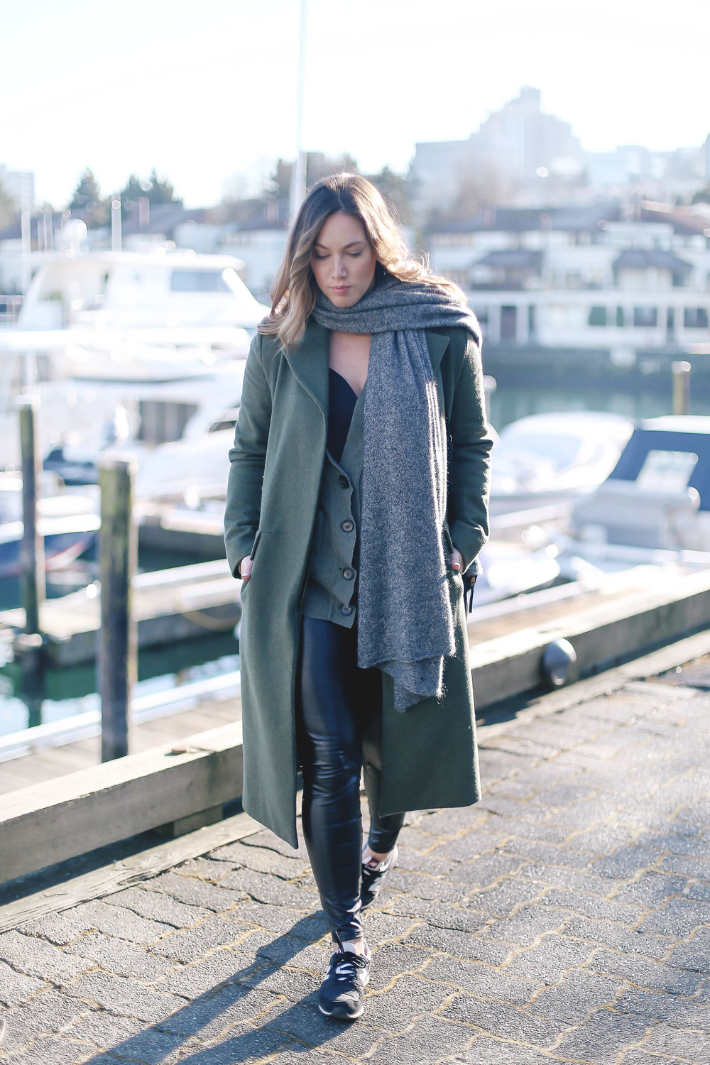 Tips to style sneakers in New Balance sneakers, a statement green coat, leather leggings and cashmere cardigan