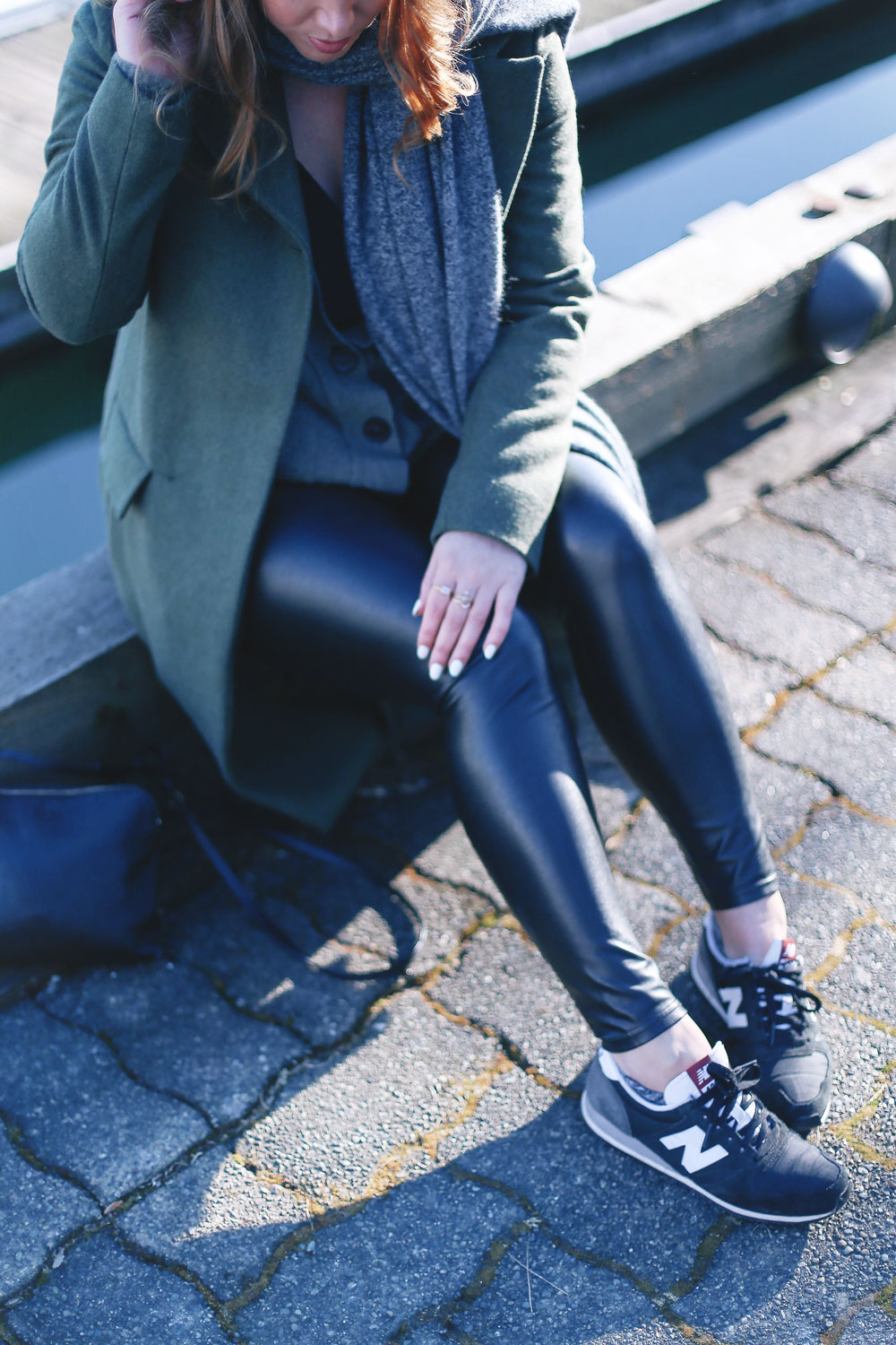 Tips to style sneakers in New Balance sneakers, a statement green coat, leather leggings and cashmere cardigan