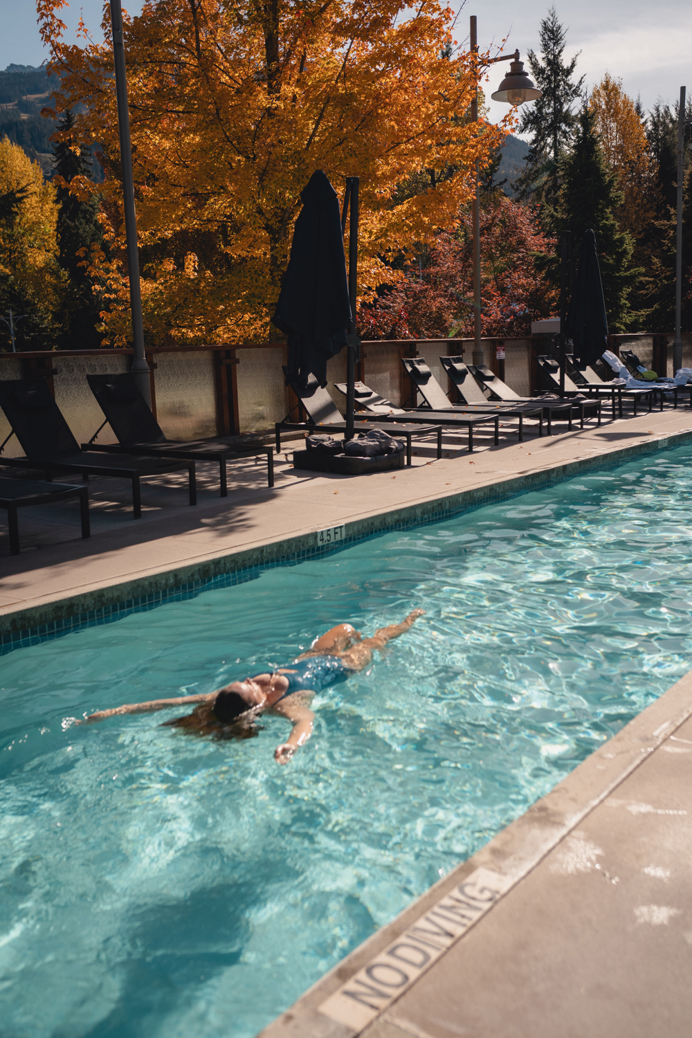 Outdoor heated pool surrounded by fall foliage at Pan Pacific Whistler Village Centre